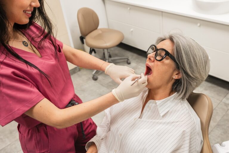 A nervous patient in a dental chair is being comforted by a dentist and an anesthesiologist who are smiling reassuringly; the anesthesiologist is holding a syringe. No text on the image.